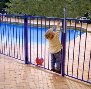 Small boy attempting to open pool gate to recover his ball